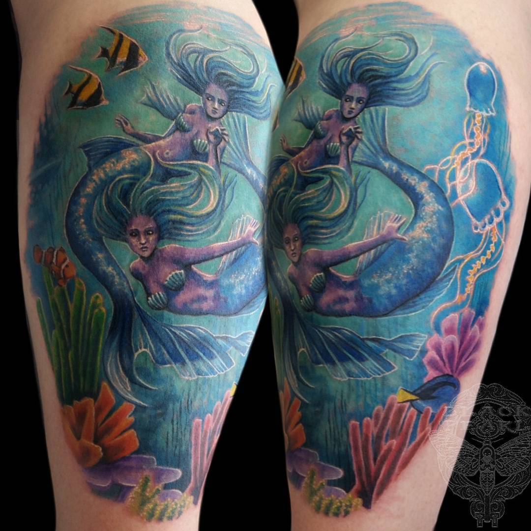 tattoo of two mermaids swimming in the blue ocean