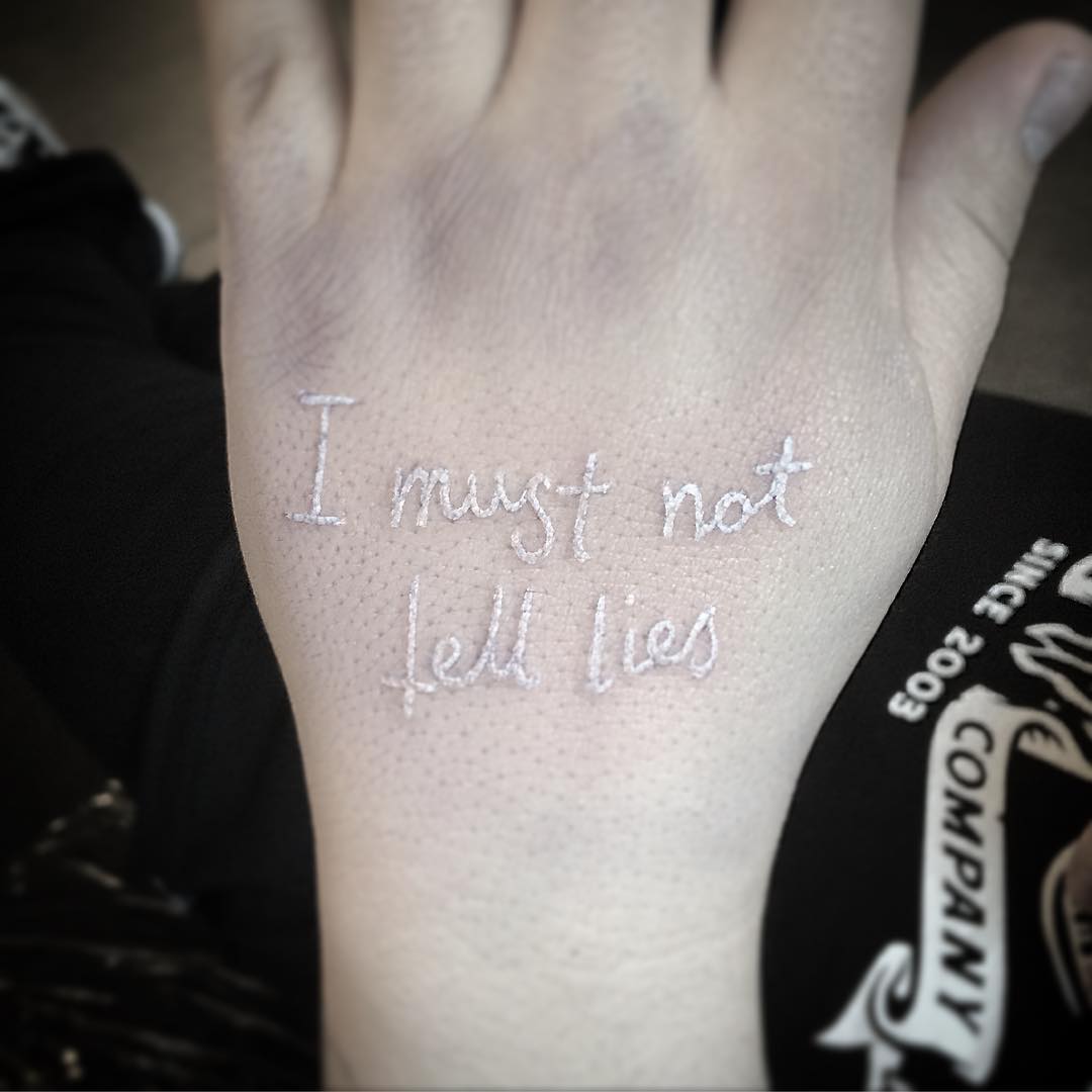 White Lettering Tattoo on Hand by AJ McGuire