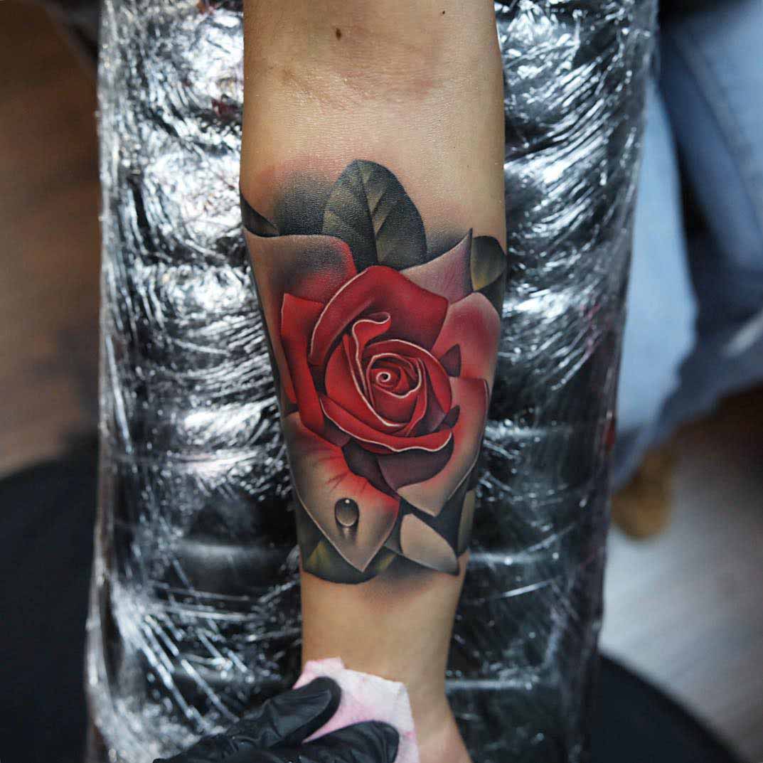 rose tattoo on arm with dew drop